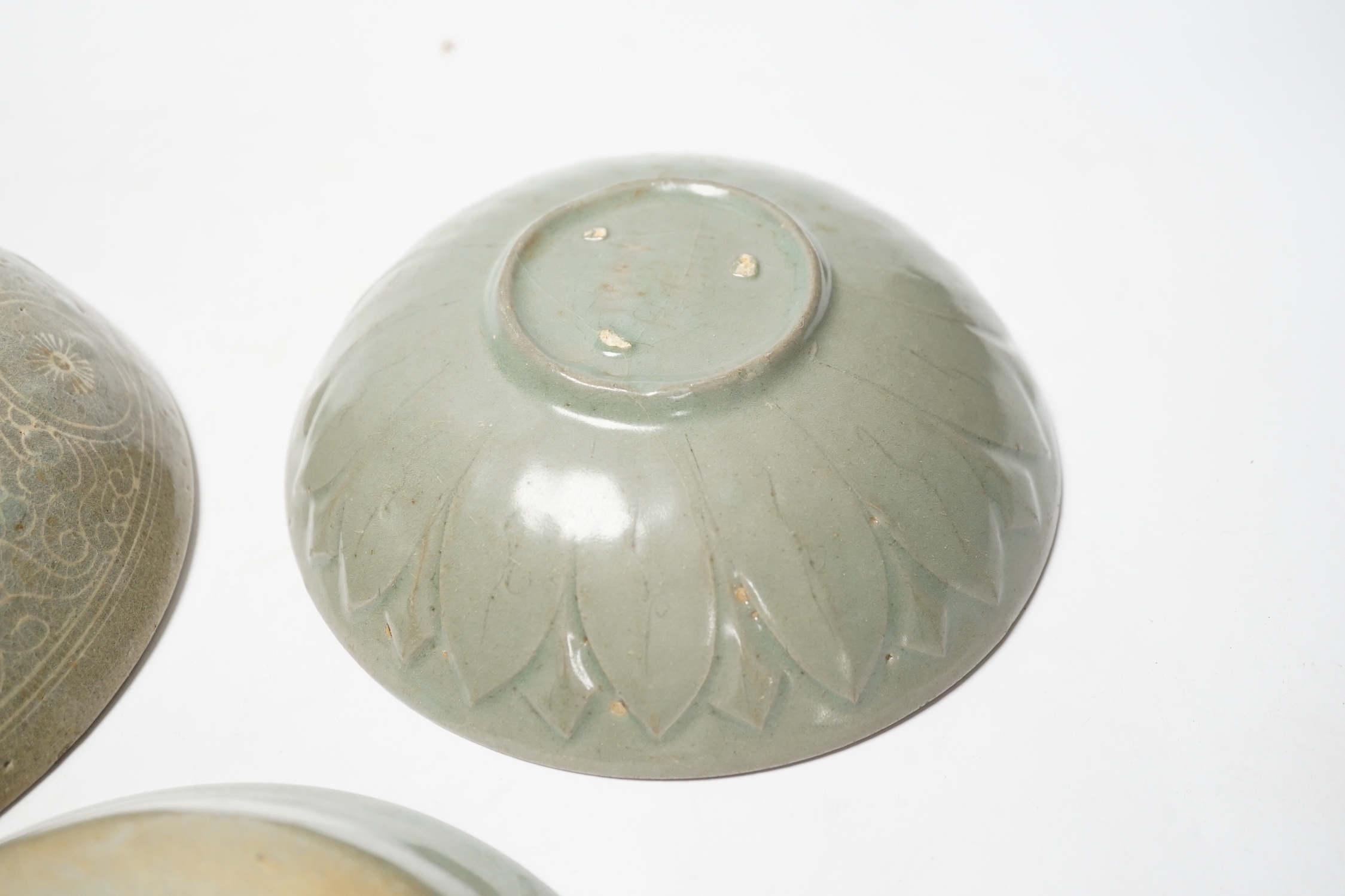 Two Korean celadon bowls, Goryeo dynasty (11th/12th century), the first carved with lotus petals to the underside, the second with fine crackle to the glaze, and a Korean slip-decorated celadon bowl (11th/12th century),